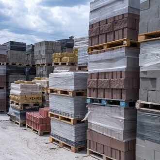 Industrial production of building cement pressed materials. High quality hollow concrete block or cement brick and paving stones. Finished products on pallets packed in film are waiting to be shipped.